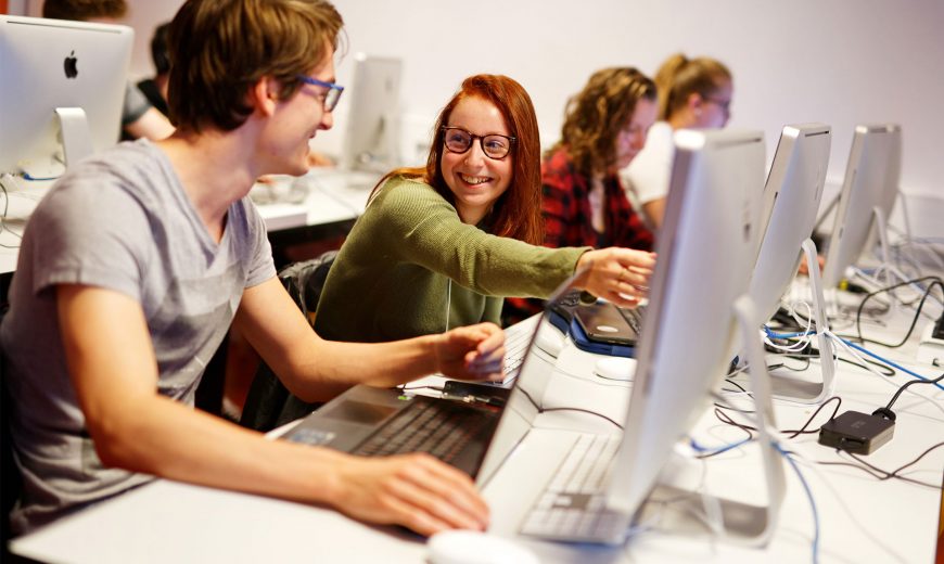 personnes qui travaillent et discutent dans une salle informatique